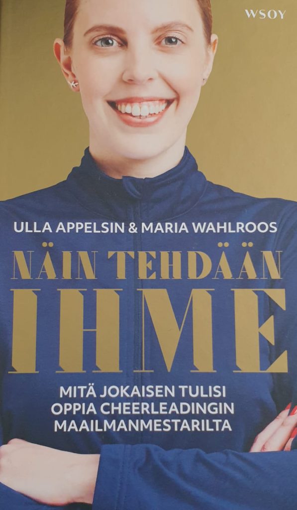 Kuvassa kirjan kansi. Kannessa Maria Wahlroos kultaisella taustalla. Maria hymyilee ja hänen kätensä on puuskassa. Päällään Marialla on sininen treenitakki.